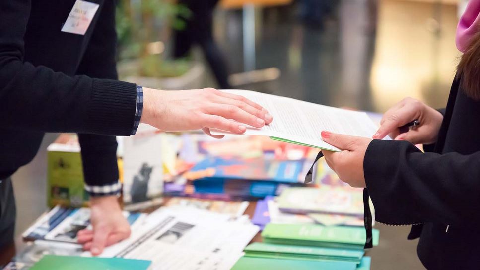 image of someone sharing handouts at a community center