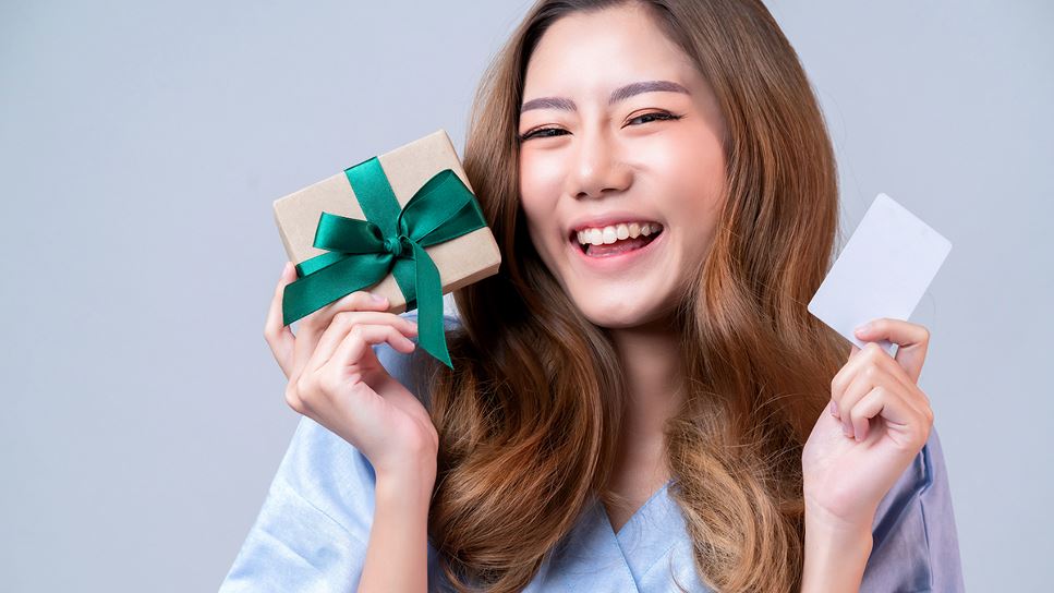 holding a gift box wrapped with a green ribbon