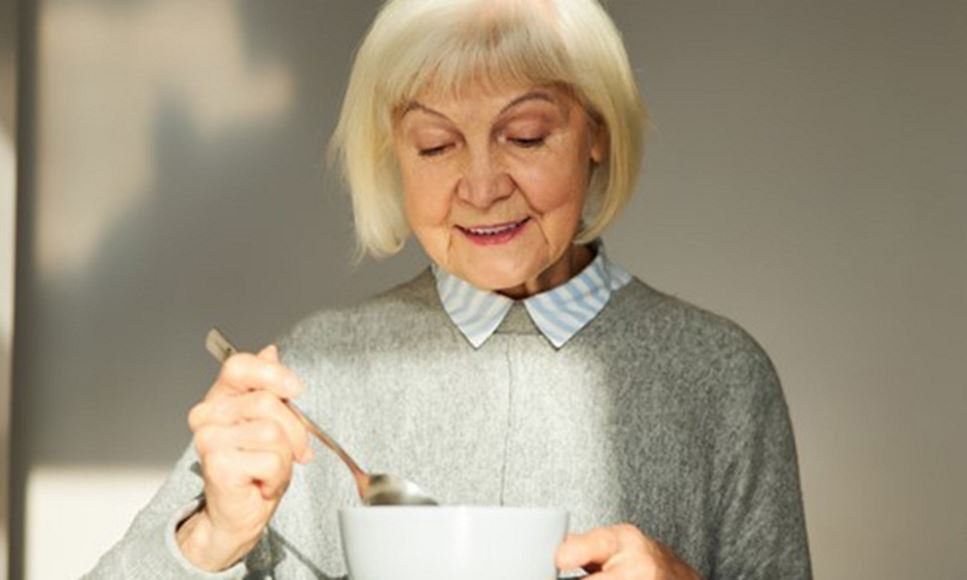 Older woman smiling over a bowl of food