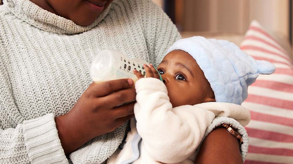 Mother holding baby, feeding them with a bottle of milk