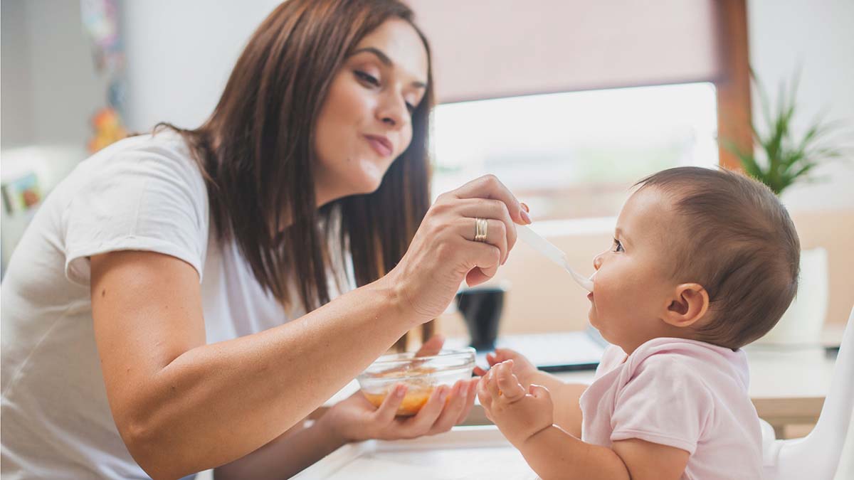 Infant Feeding Strategies to Prevent Food Allergies | Mother Feeding Baby in High Chair