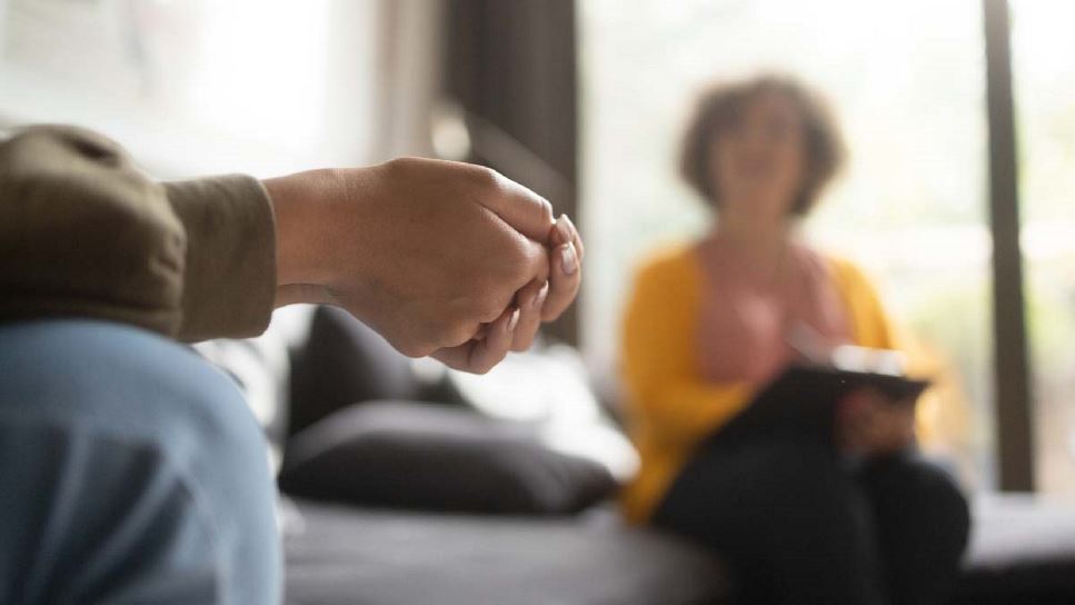 Insights into Eating Disorder Treatment: A Fundamental Exploration for Dietitians | Patient holding hands while medical professional, who is blurred in the background, is taking notes