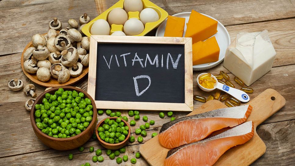 The Broad Importance of Vitamin D in Health | A wooden table with mushrooms, peas, chees and fish, as well as a chalkboard with Vitamin D written on it.