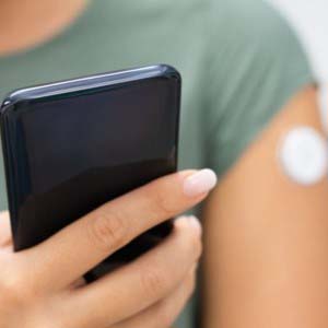 Person in green shirt holding a cell phone