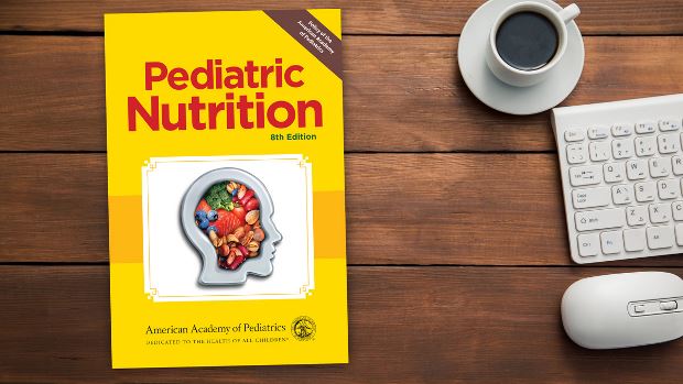 Copy of Pediatric Nutrition, 8th Ed. lying on a desk.